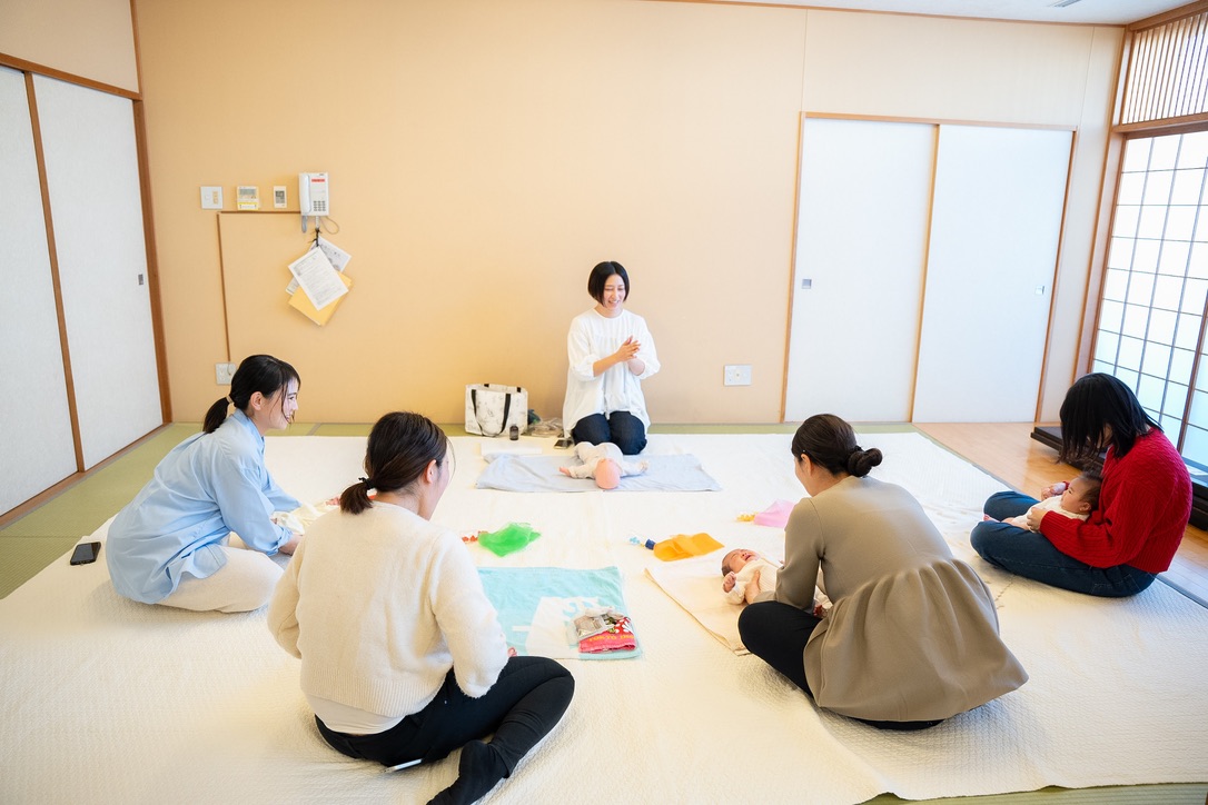 タッチケアレッスンの様子(ママたちの輪の中で赤ちゃんとふれあう講師)